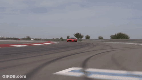 A Red Sports Car Is Driving Down A Road GIF