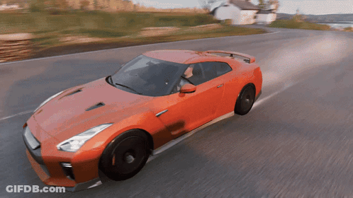 A Red Sports Car Is Driving Down A Road With A White House In The Background GIF