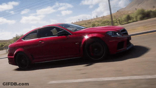 A Red Sports Car Is Driving Down A Road With Mountains In The Background GIF