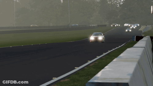 A Red Sports Car Is Driving Down A Track With Its Headlights On GIF