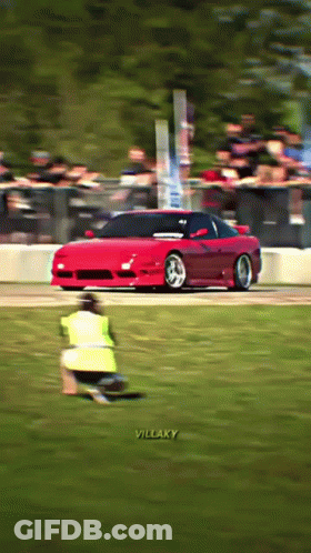 A Red Sports Car Is Driving Down A Track With The Words Villaky On The Bottom Right GIF