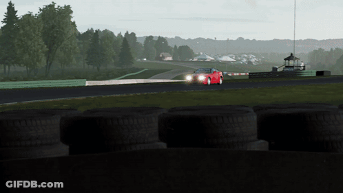 A Red Sports Car Is Driving Down A Track With Tires In The Foreground GIF