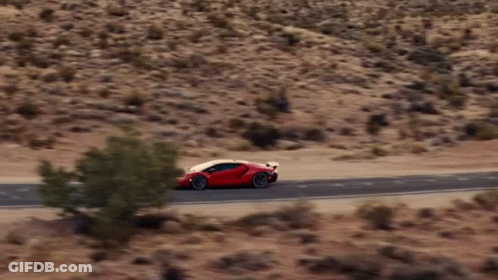 A Red Sports Car Is Driving On A Desert Road GIF