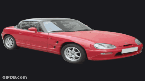 A Red Sports Car With A Black Top And Silver Wheels GIF