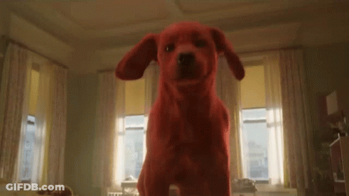 A Red Stuffed Dog Is Standing In A Living Room . GIF