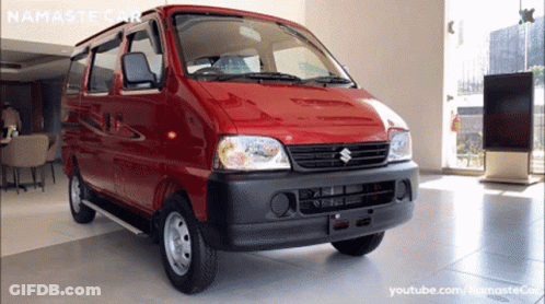 A Red Suzuki Van Is Displayed In A Showroom GIF