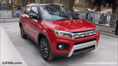 A Red Suzuki Vitara Is Parked In A Parking Lot . GIF