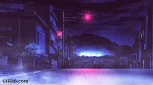 A Red Traffic Light Is Lit Up At Night In A City GIF