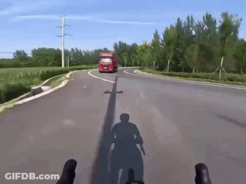 A Red Truck Driving Down A Road With A Shadow Of A Person On The Ground GIF