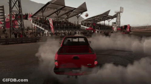 A Red Truck Is Driving Down A Track With Smoke Coming Out Of The Back GIF