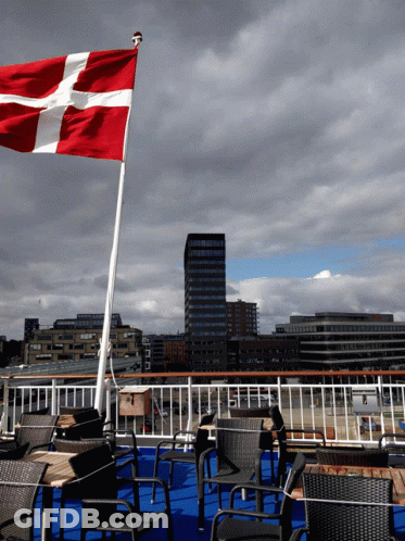 A Red White And Blue Flag Is Flying In The Wind On A Cloudy Day GIF