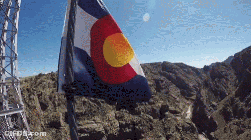 A Red White And Blue Flag With A Yellow Center Is Flying In The Wind GIF