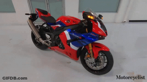 A Red White And Blue Honda Motorcycle Is Parked In A Room GIF