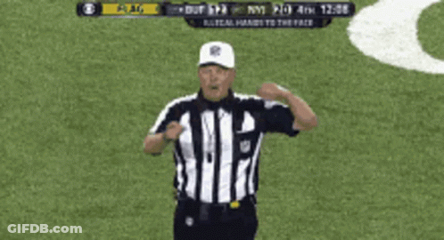 A Referee Giving A Signal On A Field With A Scoreboard Behind Him GIF