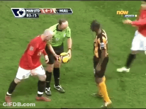 A Referee Holds A Soccer Ball Between Two Soccer Players During A Game Between Man Utd And Hull GIF