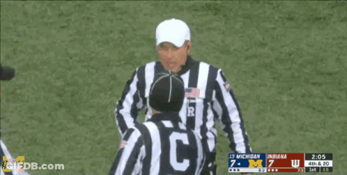 A Referee Holds Up A Yellow Flag During A Football Game GIF
