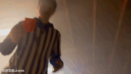 A Referee In A Striped Shirt Is Holding A Red Card In His Hand . GIF