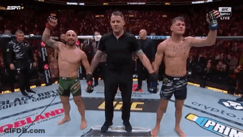 A Referee Is Standing Between Two Men In A Boxing Ring . GIF