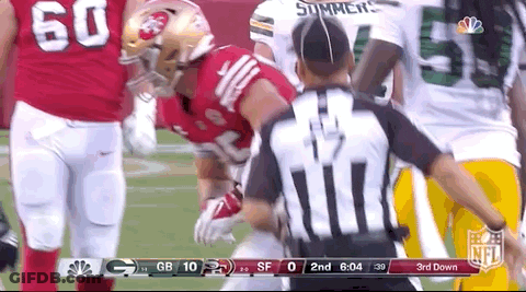 A Referee Is Standing In Front Of A Football Player During A Game . GIF
