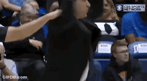 A Referee Is Standing In The Stands During A Basketball Game And Talking To A Player . GIF