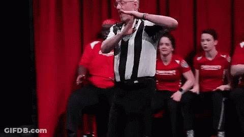A Referee Is Standing On A Stage Talking To A Group Of People . GIF