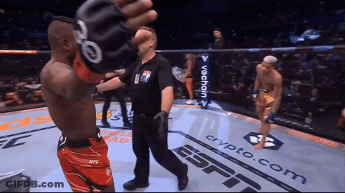 A Referee Stands In A Boxing Ring With Espn Written On The Floor GIF
