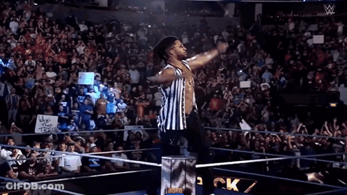 A Referee Stands In Front Of A Crowd With A Sign That Says Whos That Trash GIF