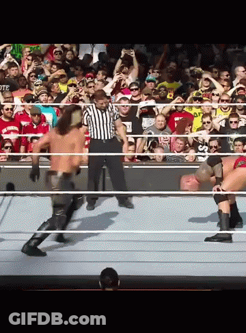 A Referee Stands In The Middle Of A Wrestling Match Between Two Men GIF