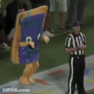 A Referee Stands Next To A Mascot Wearing A Purple Costume GIF