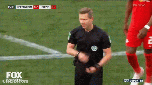 A Referee Stands On A Soccer Field With The Fox Deportes Logo On The Bottom GIF