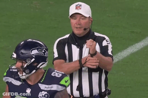 A Referee Wearing A Nfl Hat Talks To A Football Player GIF