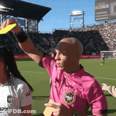 A Referee Wearing A Pink Shirt With The Word Pro On It Holds Up A Yellow Card GIF