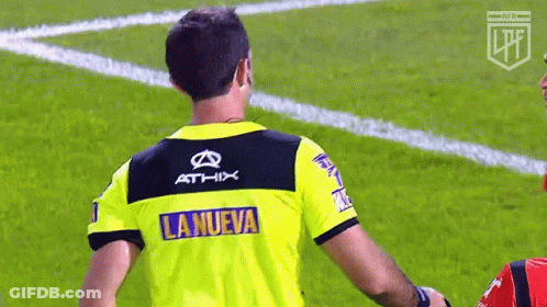 A Referee Wearing A Yellow Shirt With The Word La Nueva On It GIF