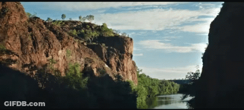 A River Runs Through A Canyon Surrounded By Trees And Rocks GIF