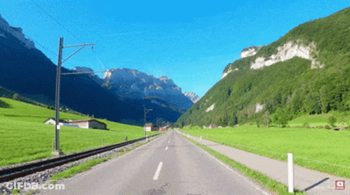 A Road Going Through A Valley With Mountains On The Horizon GIF