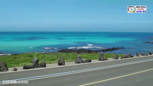 A Road Going Towards The Ocean With A Sign That Says 4K Uhd On It GIF