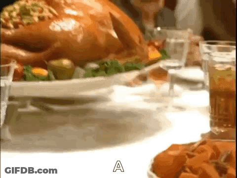 A Roasted Turkey Is Sitting On A White Plate On A Table Next To A Glass Of Wine . GIF