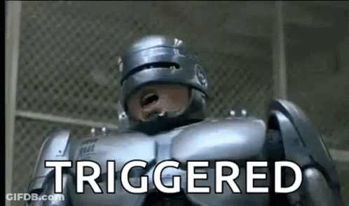A Robot Is Standing In Front Of A Fence And Says `` Triggered '' . GIF