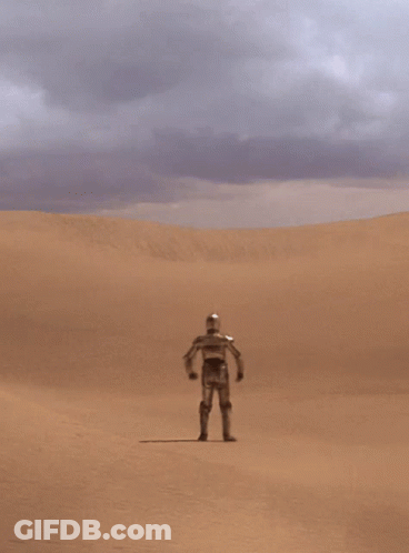 A Robot Stands In The Middle Of A Desert With His Hands On His Hips GIF