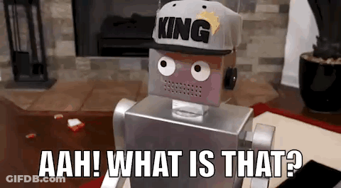 A Robot Wearing A Hat With The Word King On It Is Sitting On The Floor In A Living Room . GIF