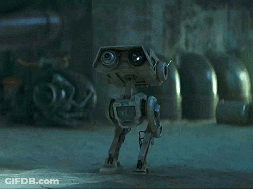 A Robot With A Camera On It 'S Head Is Walking On The Ground In A Dark Room . GIF