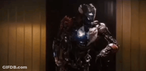 A Robot With A Helmet On Is Standing In A Doorway . GIF