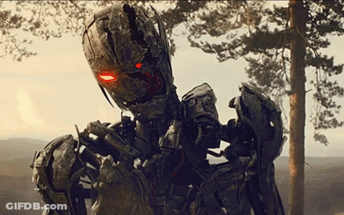 A Robot With Red Eyes Is Standing In Front Of A Tree GIF