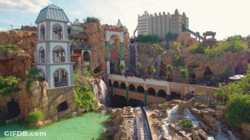 A Roller Coaster With A Waterfall In The Background And A Building That Says ' Eiffel Tower ' On The Side GIF