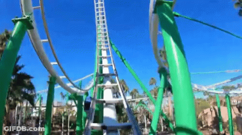 A Roller Coaster With Green Poles And A Blue Sky In The Background . GIF