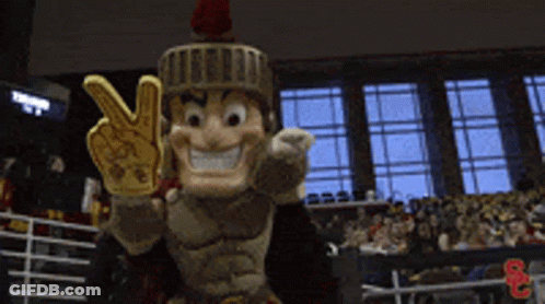A Roman Soldier Mascot Is Giving A Peace Sign In Front Of A Crowd GIF