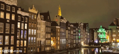 A Row Of Buildings Next To A Body Of Water With A Green Building In The Foreground GIF