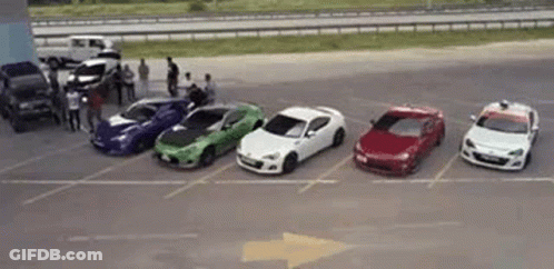 A Row Of Cars Are Parked In A Parking Lot Next To Each Other . GIF