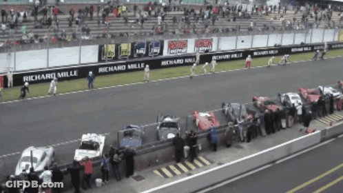 A Row Of Cars Are Parked On A Race Track With Richard Mille Advertisements GIF