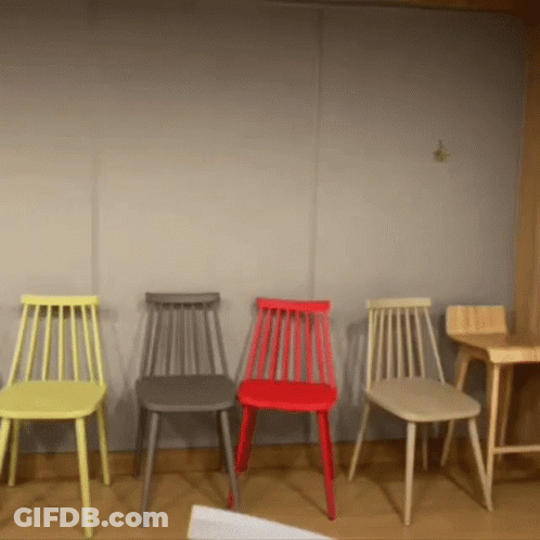 A Row Of Chairs Of Different Colors Are Lined Up In A Room GIF